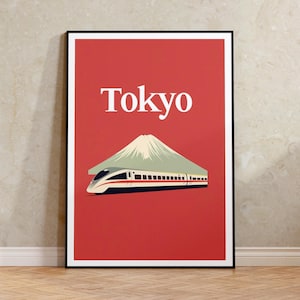 May include: A framed art print featuring a red background with the white word "Tokyo" at the top. Below, a stylized image of Mount Fuji and a high-speed train. The print has a black frame.