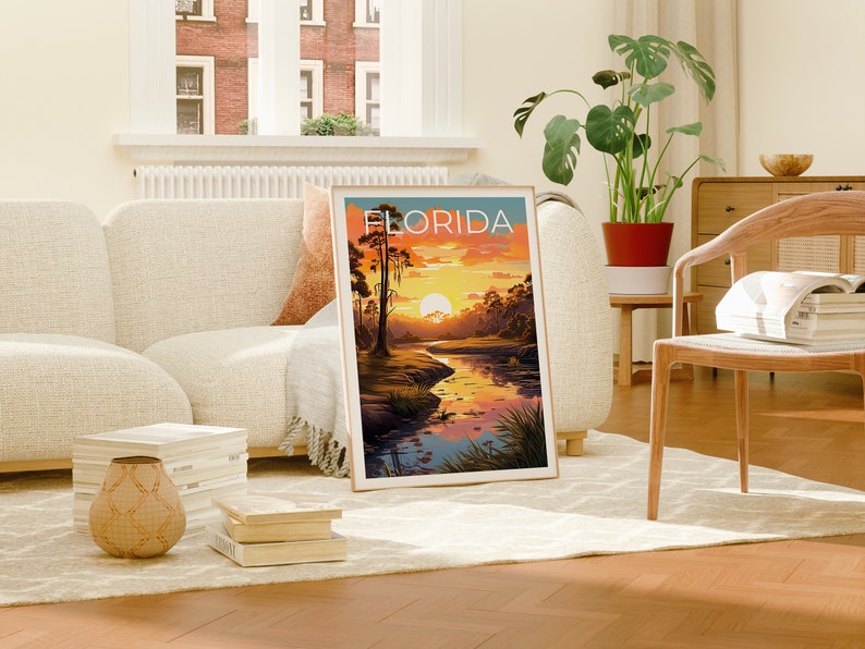 K&ouml;nnte beinhalten: Ein gerahmtes Poster mit einer Sonnenuntergangsszene &uuml;ber einem Fluss in einem Sumpf. Das Poster tr&auml;gt den Titel "FLORIDA" in wei&szlig;er Schrift.