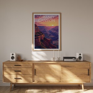 May include: A wooden dresser with three drawers and a cabinet door. The dresser is in a room with a framed poster of the Grand Canyon with the text "GRAND CANYON" on it. There are two white speakers on the dresser, a small silver object, and a black stereo.