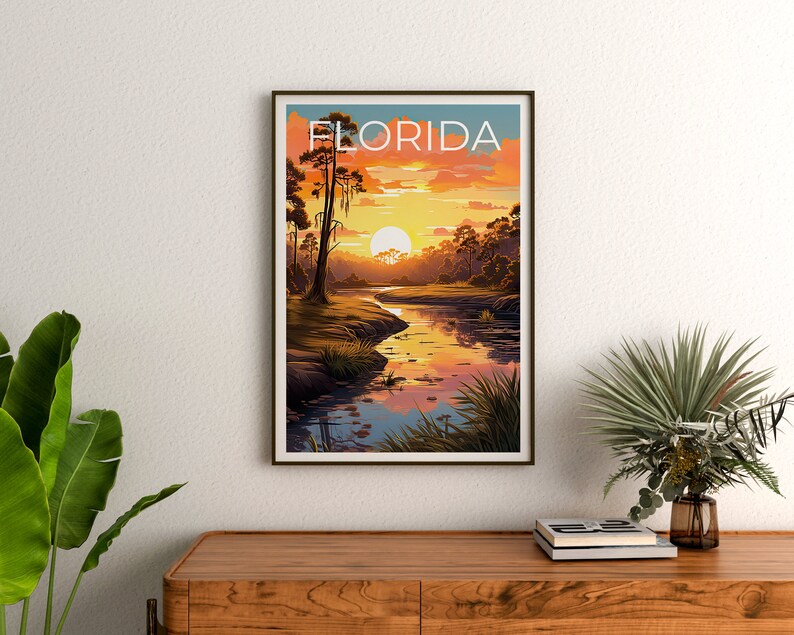 K&ouml;nnte beinhalten: Ein Vintage-Reiseposter mit einer Sonnenuntergangsszene &uuml;ber einem Fluss in Florida. Das Poster zeigt eine gro&szlig;e, orange Sonne, die hinter einer Baumreihe untergeht, und einen Fluss, der durch die Szene flie&szlig;t. Der Text "FLORIDA" ist in fetter, wei&szlig;er Schrift oben auf dem Poster gedruckt.