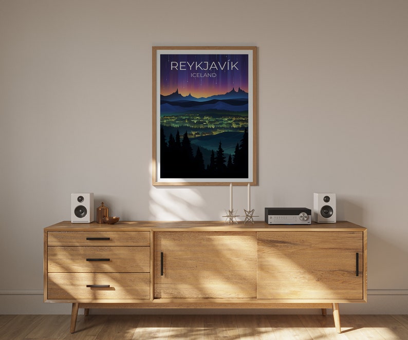May include: A framed poster featuring a cityscape illustration of Reykjavik, Iceland. The poster has a dark blue background with a purple and orange gradient. The city is depicted in silhouette with lights illuminating the buildings. The text "REYKJAVIK" and "ICELAND" is printed in white at the top of the poster.