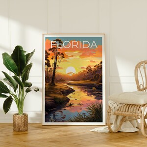 K&ouml;nnte beinhalten: Ein Vintage-Poster mit dem Wort "FLORIDA" in wei&szlig;er Schrift auf blauem Hintergrund. Das Poster zeigt einen Sonnenuntergang &uuml;ber einem Fluss mit Zypressen und der Spiegelung der Sonne im Wasser.