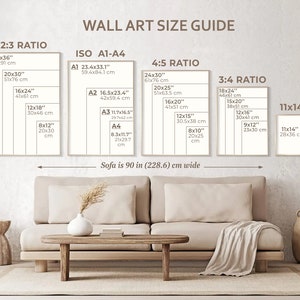 May include: A wall art size guide with different ratios and measurements in inches and centimeters. The guide shows the dimensions of various sizes of wall art, including 2:3, 4:5, 3:4, and 11x14 ratios. The guide also includes standard ISO paper sizes A1, A2, A3, and A4. The guide is displayed on a wall with a beige sofa and a coffee table in front of it.