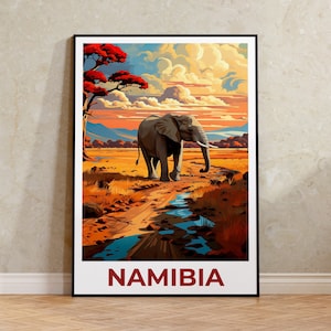 May include: Framed art print depicting an elephant on a dirt track in Namibia. The artwork displays a vivid sunset with orange, yellow, and blue tones. The word "NAMIBIA" is printed in red at the bottom of the image.