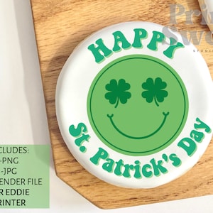 May include: White round cookie with green frosting. The frosting is shaped like a smiley face with shamrock eyes and the text "Happy St. Patrick's Day".