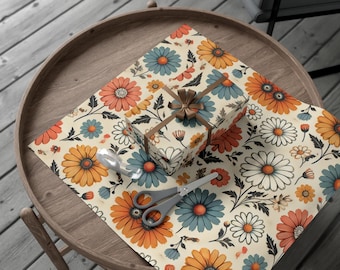 May include: A gift wrapped in floral patterned paper with orange, blue, and white flowers. The paper is on a wooden table with a pair of scissors and a roll of tape.