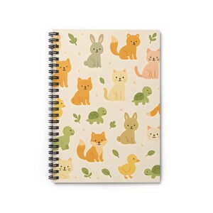 Puede incluir: Un cuaderno de espiral con una cubierta de color crema que presenta un patrón repetitivo de animales de dibujos animados, incluidos zorros, gatos, conejos, tortugas y patos. Los animales están en tonos de naranja, amarillo, verde y marrón.