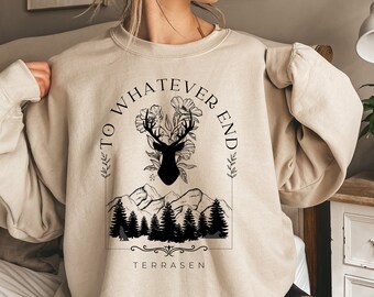 May include: A beige sweatshirt with a black graphic print of a deer with antlers, flowers, and mountains. The text "To Whatever End" is written in a circle around the deer. The text "Terrassen" is written below the graphic.
