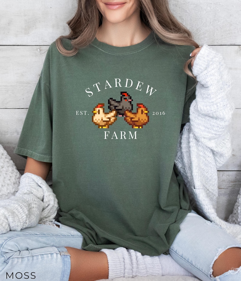 May include: A green t-shirt with a white graphic of three pixelated chickens and the text "Stardew Farm Est. 2016".