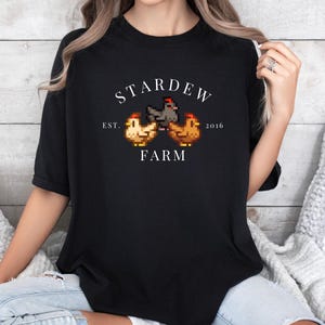 May include: Black t-shirt with a white graphic of three pixelated chickens and the text "Stardew Farm Est. 2016".