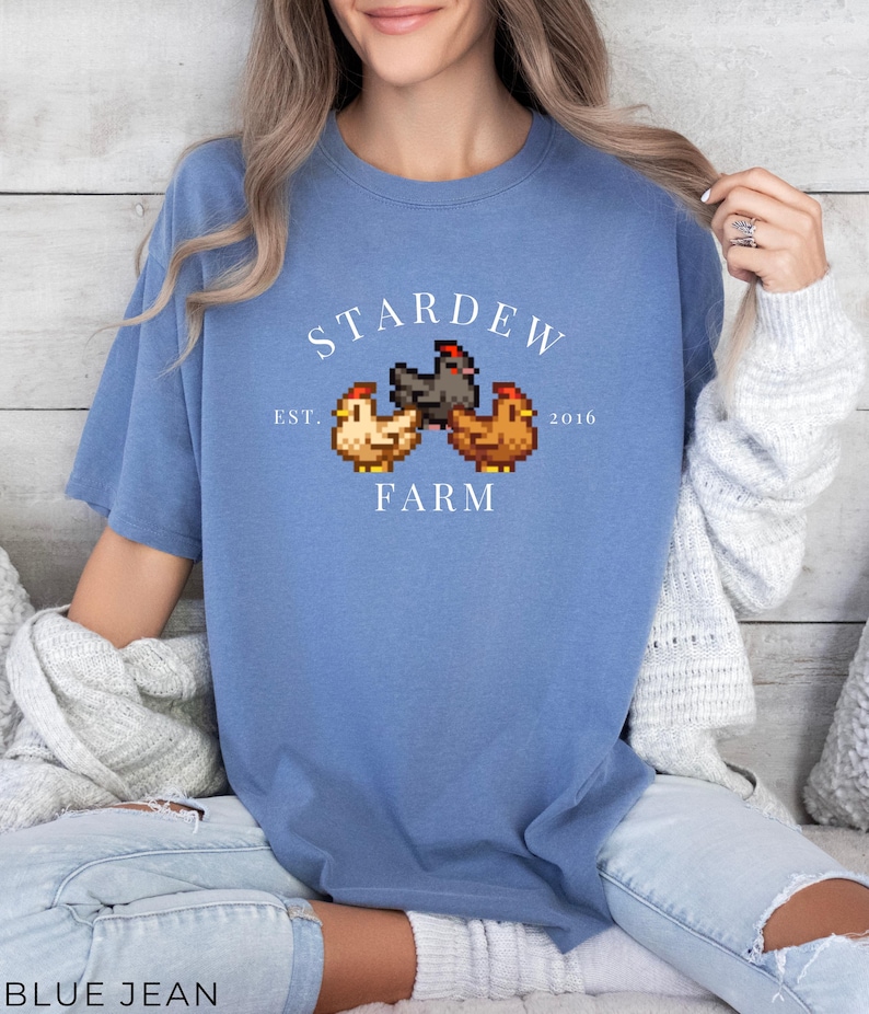 May include: A blue t-shirt with a white graphic of three pixelated chickens and the text "Stardew Farm Est. 2016".