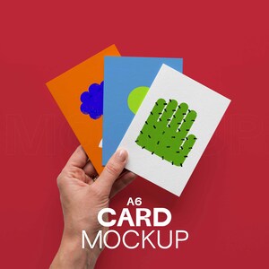 May include: A hand holds three A6 card mockups against a red background. The cards feature colorful designs: an orange card with a blue cloud, a blue card with a green circle, and a white card with a green cactus. The text "A6 CARD MOCKUP" is visible.