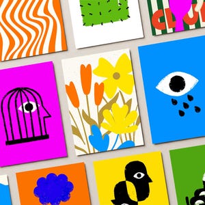 May include: A collection of colorful art prints featuring various abstract designs. The prints showcase bold colors and graphic illustrations, including floral patterns, an eye with tears, and a head inside a cage. The prints are arranged on a light background.