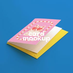 Op de afbeelding: Een gevouwen wenskaart met een roze omslag met een illustratie van een witte kat met een rode hartvormige zonnebril in een rood-wit gestreepte rand. De kaart ligt op een gele envelop. De tekst card mockup is in het wit afgedrukt.