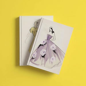Pu&ograve; includere: Due quaderni con copertina rigida con illustrazioni di moda. Un quaderno presenta un disegno di una donna in un abito viola con accenti di rose bianche. L'altro quaderno ha un disegno di una donna in un abito giallo. I quaderni sono su sfondo giallo.