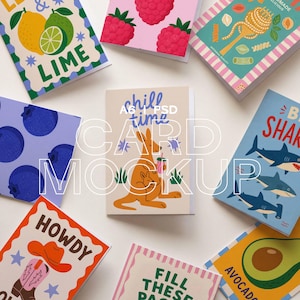 May include: A collection of colorful greeting cards with various designs, including fruits, pasta, sharks, and a kangaroo. The cards feature text such as "LIME," "chill time," and "HOWDY." The cards are arranged on a white surface.