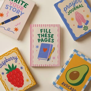 Pu&ograve; includere: Una collezione di diari colorati con vari disegni e testo. Un diario recita "Write Your Story" con un'illustrazione di penna. Un altro dice "Prayer Journal" con mani in preghiera. Altri diari presentano un lampone, un avocado e il testo "Fill These Pages".