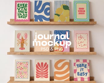Può includere: Dodici diari con copertine grafiche colorate disposti su tre mensole in legno. I design includono testi come Everything Will Be Okey, Good Vibes Ahead, Oh La La e Take It Easy, insieme a illustrazioni di un'aragosta, limoni e forme astratte.