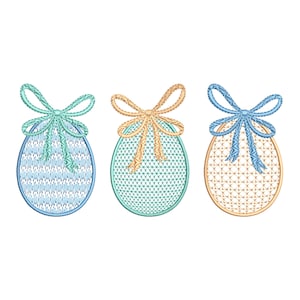 Könnte beinhalten: Drei bestickte Ostereier mit Schleifen. Die Eier sind blau, grün und orange mit weißem Hintergrund. Die Schleifen sind gelb, blau und orange.