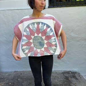 May include: A white and pink cotton top with a blue and pink circular design. The top has short sleeves and a relaxed fit.