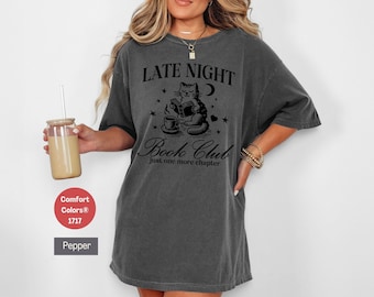 May include: A gray oversized t-shirt with a black graphic of a cat reading a book and a cup of coffee. The text on the shirt reads "Late Night Book Club Just one more chapter."