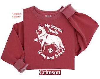 May include: A crimson red sweatshirt with the text "My Siberian Husky is my best friend" and a white silhouette of a Siberian Husky dog. The sweatshirt is made of a soft, comfortable fabric.