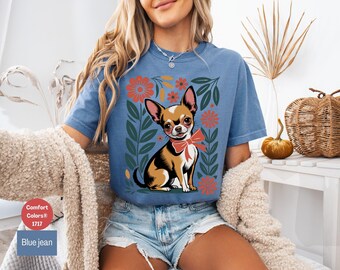 May include: A blue jean t-shirt with a floral design and a chihuahua wearing a red bow tie. The text "Comfort Colors® 1717" is printed on the bottom left corner of the shirt.