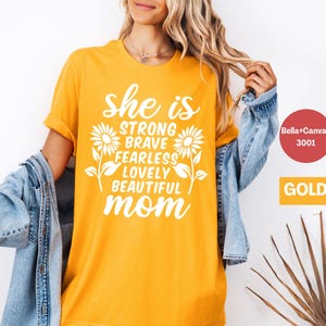 May include: Yellow t-shirt with the text "She is strong, brave, fearless, lovely, beautiful mom" with a sunflower graphic.