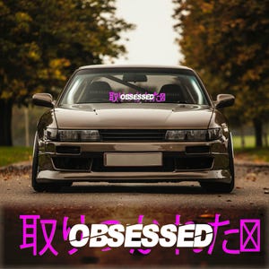 May include: A brown car with a pink and white windshield banner that says "取OBSESSEDた区".