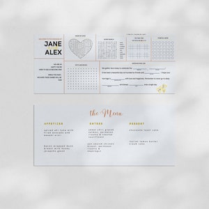 May include: A wedding menu with the title "The Menu" in gold script. The menu features appetizers, entrees, and desserts. The appetizers include spiced ahi tuna with fried avocado and wasabi aioli and bacon wrapped duck breast with honey jalapeno glaze. The entrees include sweet chili glazed salmon, parmesan risotto & roasted cauliflower and pan seared chicken breast, parmesan risotto & asparagus. The desserts include chocolate layer cake and Italian lemon butter cream cake.