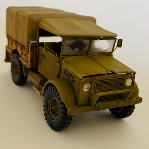 May include: A green military truck model with a canvas top and a wooden bed. The truck has a detailed front grill and headlights.