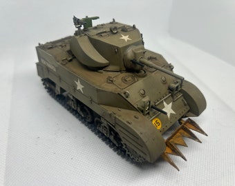 Puede incluir: Un tanque modelo verde y marrón con una estrella blanca en el lateral y un número 15 amarillo en la parte delantera. El tanque tiene una torreta grande y redondeada con un cañón apuntando hacia adelante. El tanque tiene un conjunto de púas metálicas en la parte delantera.