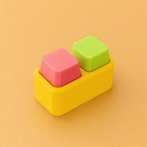 May include: A yellow rectangular container holds two square objects. One is pink, the other is green. The background is a solid orange color. The objects appear to be made of a soft material.