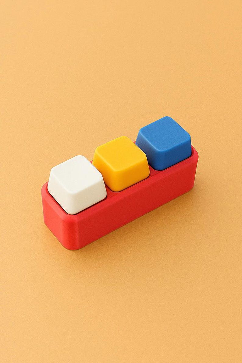 May include: A red rectangular tray holds three square blocks: white, yellow, and blue. The blocks are evenly spaced and sit flush within the tray. The background is a solid orange color.