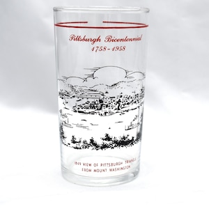 May include: Clear glass with a red rim and text that reads "Pittsburgh Bicentennial 1758-1958." The glass features a black and white illustration of a cityscape with the text "1849 View of Pittsburgh Triangle from Mount Washington."
