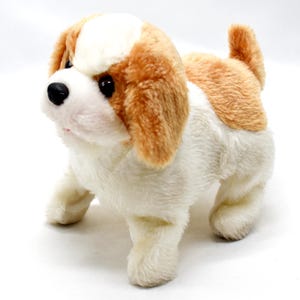 Puede incluir: Un perro de peluche con cuerpo blanco, orejas marrones y beige, y nariz negra. El perro de juguete está de pie sobre sus cuatro patas contra un fondo blanco. El pelaje del perro es suave y esponjoso, y tiene una expresión amigable.