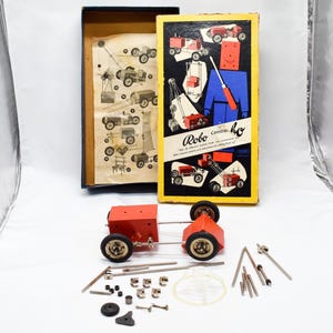 May include: Vintage Robo Centra Ho construction set with a red chassis and black wheels. The box features illustrations of the models that can be built. Includes various metal and plastic parts, and an instruction sheet. A classic toy.