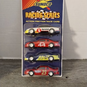 May include: A package of four Sunoco Racing Series action friction race cars. The cars are red, white, and yellow with various sponsors including Kendall, Slim Jim, 83, and Twizzlers. The cars are 1:28 scale.