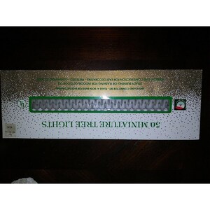 May include: A box of 50 miniature tree lights with a white background and green text. The box has a gold border and a small green logo in the top right corner. The lights are shown in a row on the box, with a white wire connecting them.