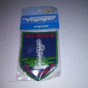 May include: A blue and green embroidered patch with the text "Old Faithful" and "Yellowstone NP" in red. The patch features a white geyser erupting from a green field.
