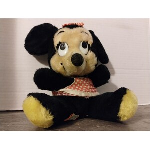 Puede incluir: Un juguete de peluche vintage de Minnie Mouse con un vestido de lunares rojos y blancos. El juguete tiene pelo negro, pies amarillos y grandes ojos negros.