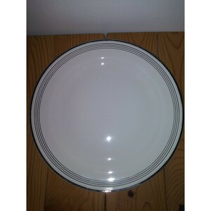 May include: White ceramic dinner plate with a black rim and three thin black lines around the edge.