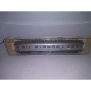 May include: A silver model train car with red accents and windows. The car is in a clear plastic case with the word "Fleischmann" printed on the side.