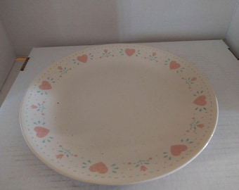 Pode incluir: Um prato de cerâmica branco com um design floral rosa e verde com corações ao redor da borda.