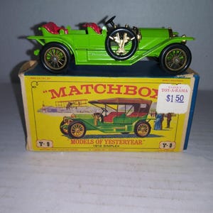 May include: A green 1912 Simplex toy car in a yellow Matchbox box. The box has the text "Matchbox" and "Models of Yesteryear" printed on it. The box also has a price tag that says "$1.50".