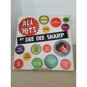 May include: Vintage vinyl record album cover for "All The Hits" by Dee Dee Sharp. The cover features a red and yellow burst design with the album title and artist's name. Song titles are in colorful starbursts.