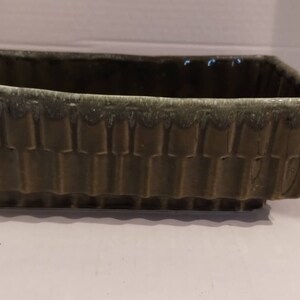 May include: A rectangular green ceramic planter with a textured, bamboo-like design. The planter has a light green glaze and a slightly uneven rim.