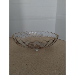May include: A clear glass pedestal bowl with a scalloped rim and gold leaf floral design.