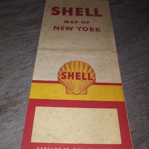May include: A vintage Shell gas station map of New York. The map is folded and has a red, yellow, and white color scheme. The Shell logo is a yellow seashell on a red background. The text "SHELL MAP OF NEW YORK" is printed in red on a white background. The text "SERVICE IS OUR BUSINESS" is printed in white on a red background.