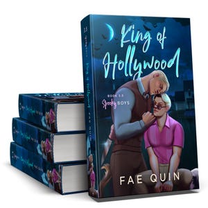 May include: A stack of books with the cover art of "King of Hollywood" by Fae Quin. The cover features two men, one in a pink shirt and the other in a brown vest. The title is in teal script against a dark blue background.